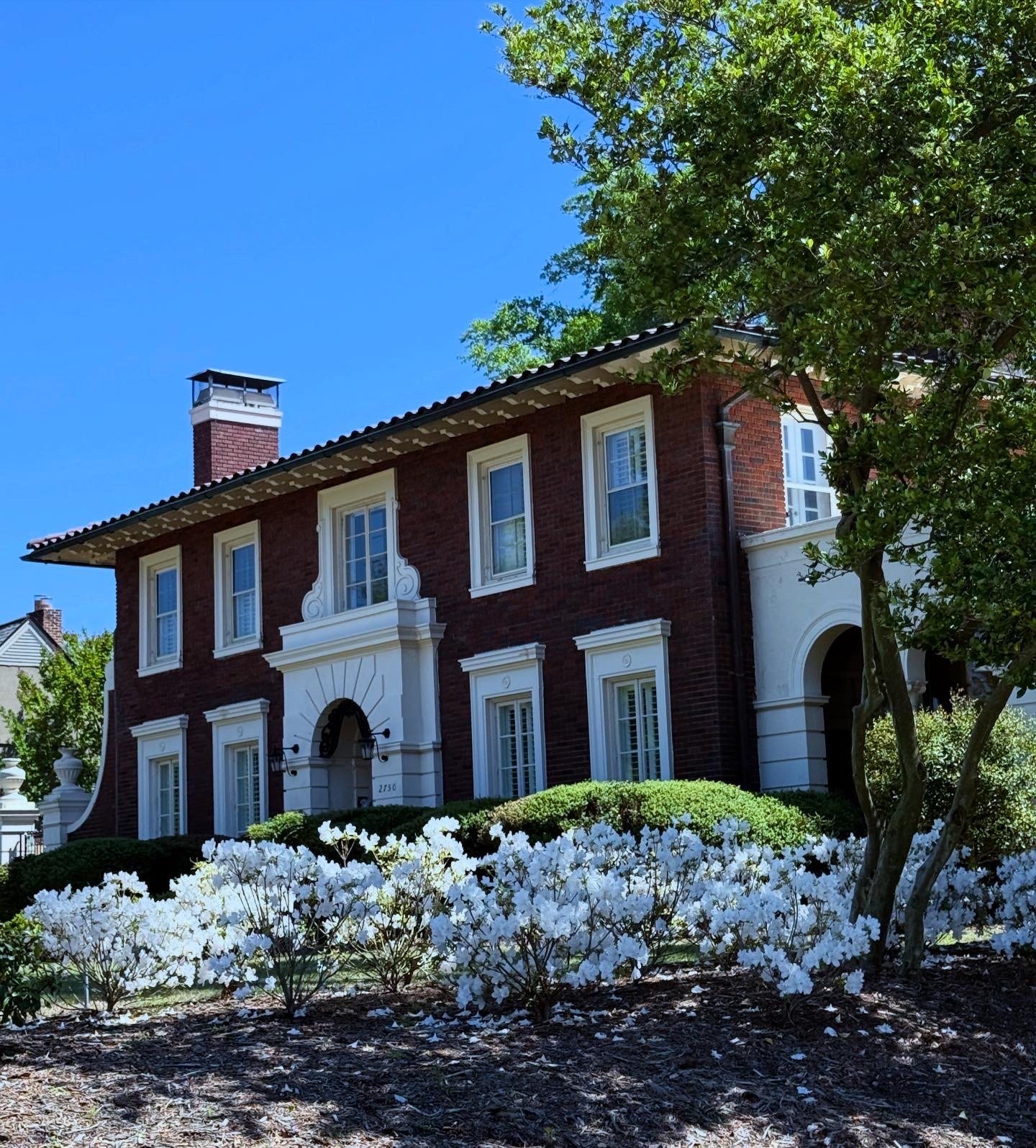 Brick Italianate two-story home with a red tile roof and white azaleas blooming out front, Augusta, Georgia, architectural photography by Nelson White