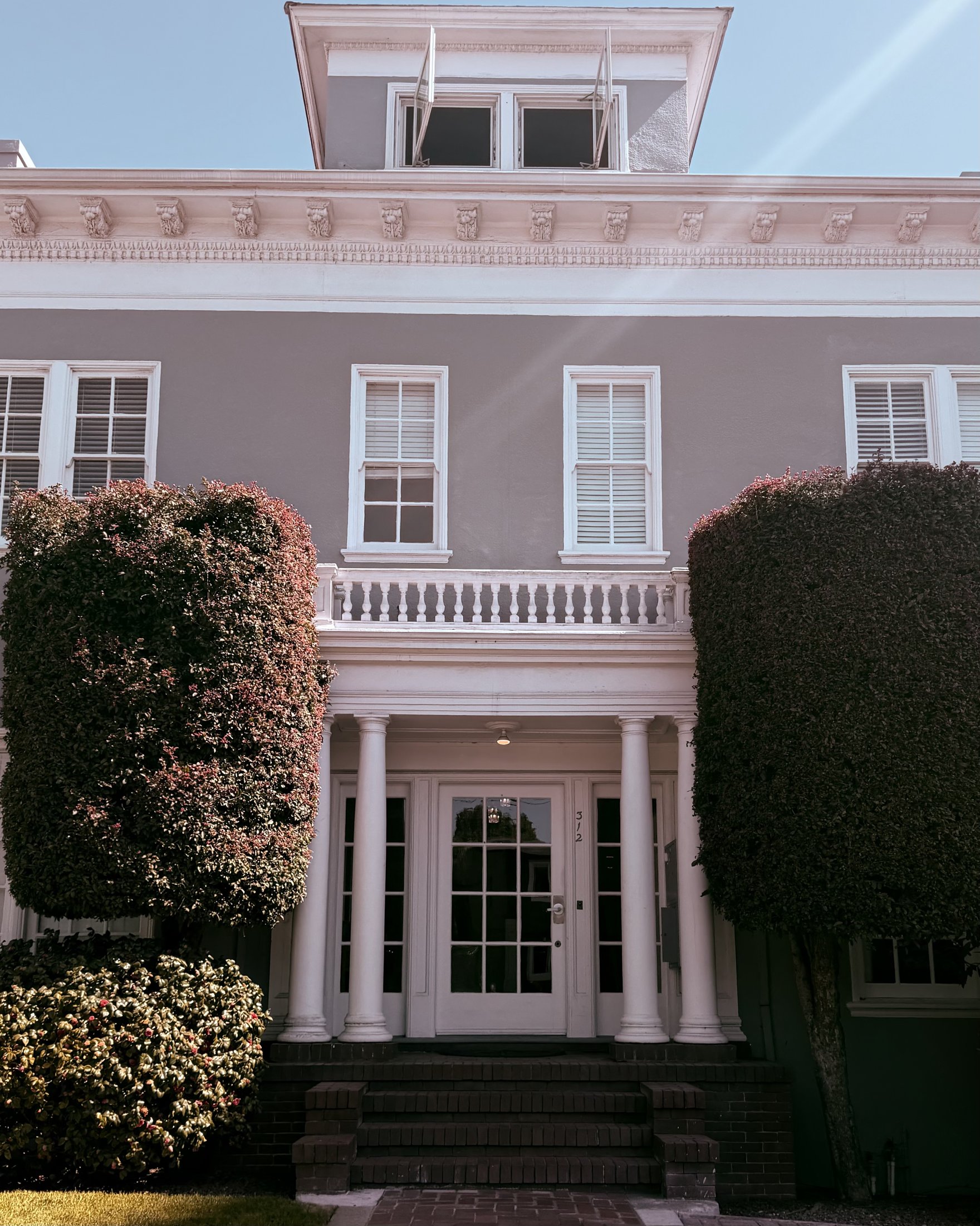 Pink Classical Revival home with a formal columned entry and sculpted hedges, Bay Area, California, architectural photography by Nelson White