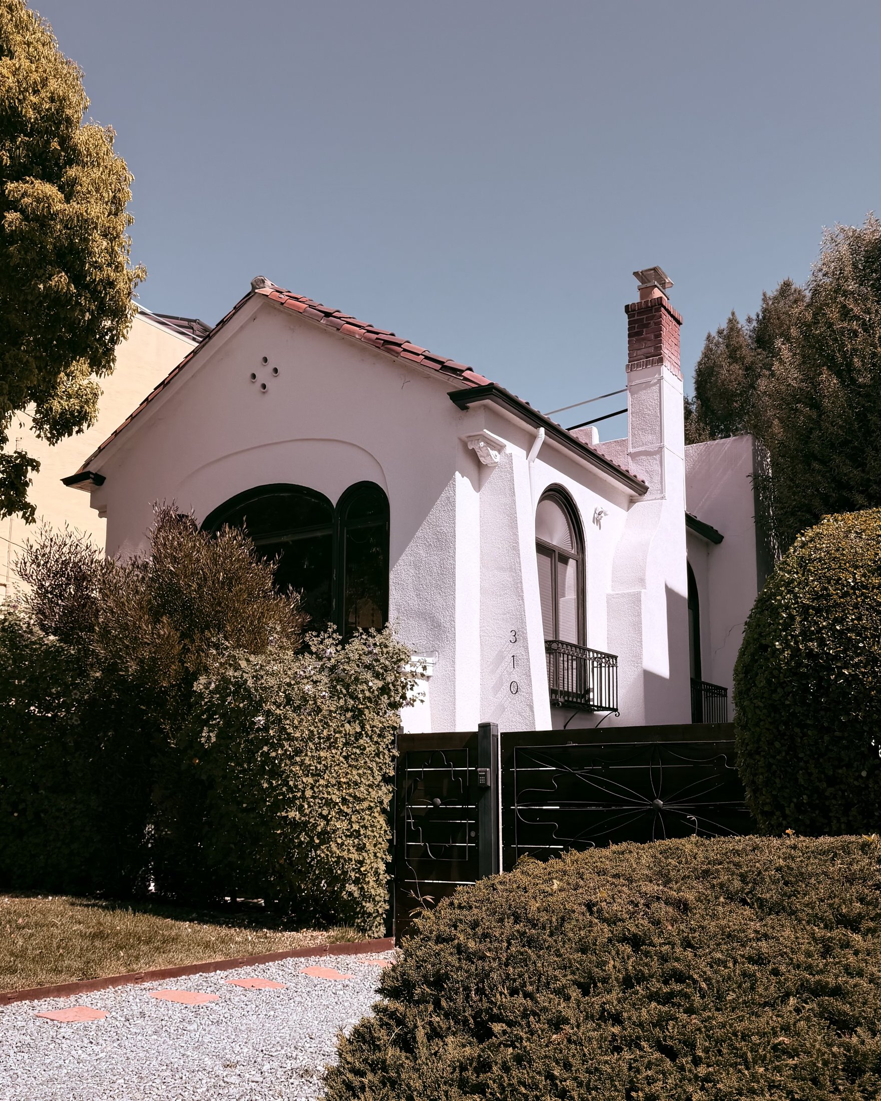 White Spanish-style stucco house with arched windows and tile-roof accents, Bay Area, California, architectural photography by Nelson White